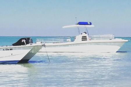 Two white boats float on calm, turquoise water under a clear blue sky.